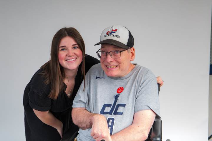 A woman and a smiling man in a ball cap pose together