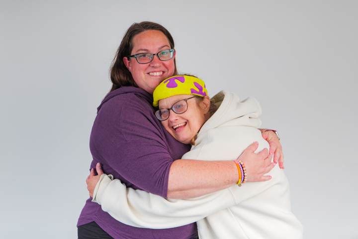 Two women share a warm hug and smile